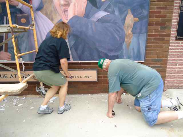 Artists Julie Krovicka and Don Gray inspect the murals panels and discuss restoration.